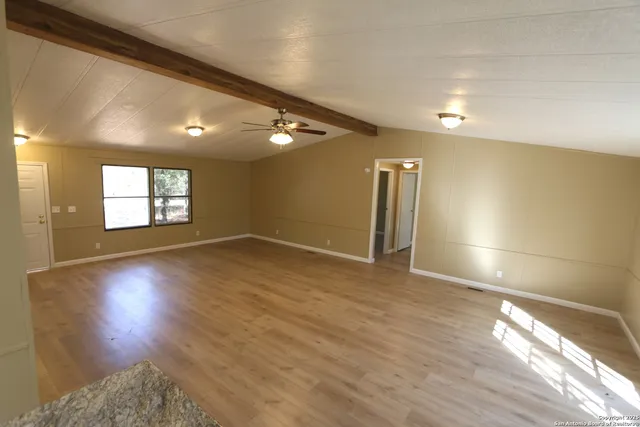 a view of empty room with window and wooden floor
