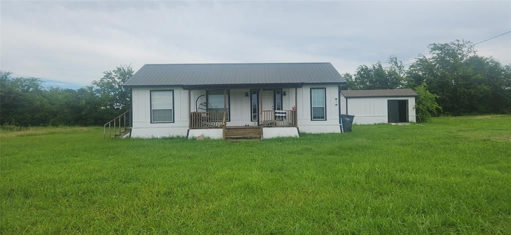 3133 Tbd County Road Lone Oak, TX 75453 - Photo 1 of 21 White siding residence featuring a dark metal roof, front porch with wooden railings, and multiple windows with dark trim