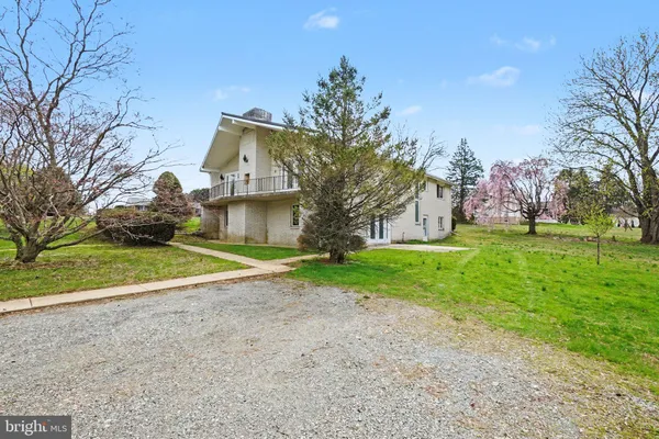 a view of a house with a big yard and large trees
