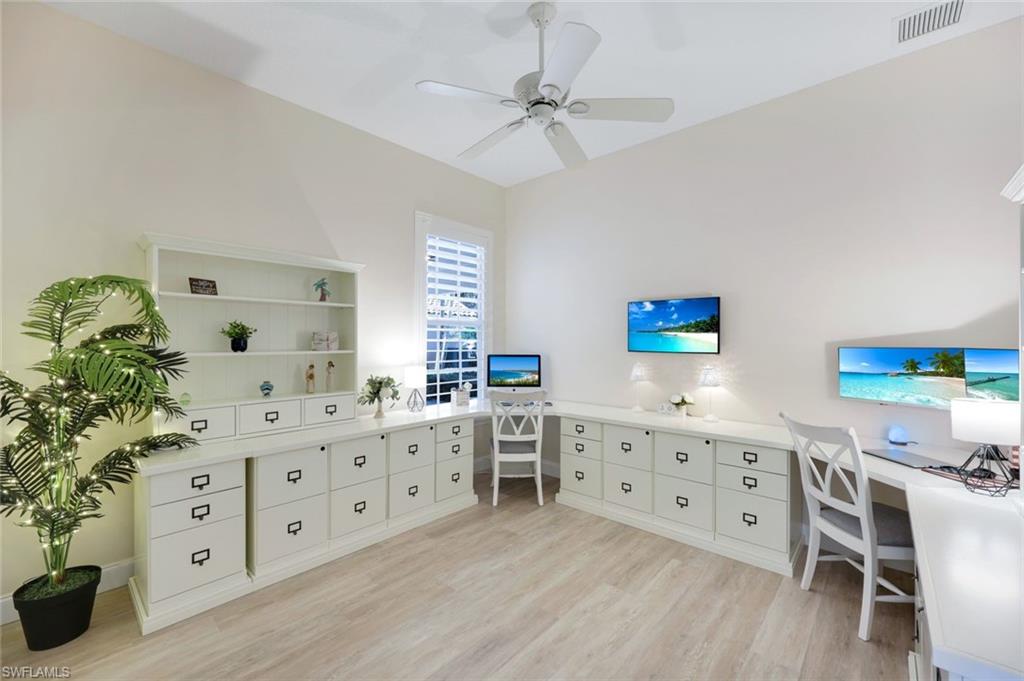 3108 Dominica Way Naples, FL 34119 - Photo 17 of 39 Dedicated workspace featuring extensive built-in cabinetry, wood-finish flooring, and a ceiling fan. This fourth bedroom is currently set up as a home office.