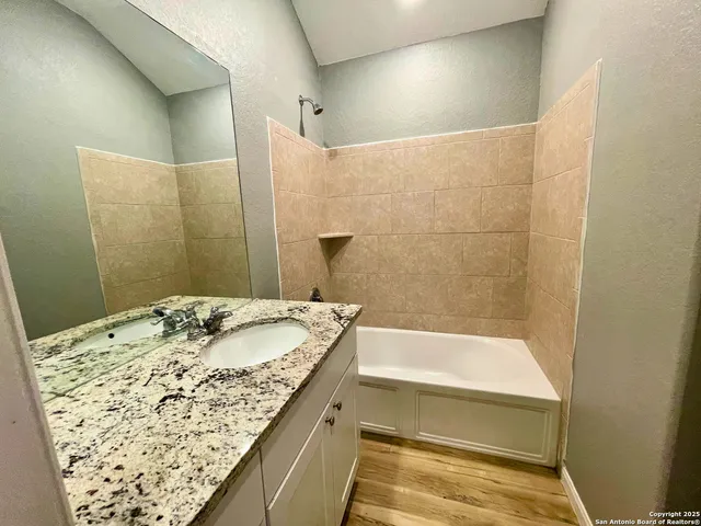 a bathroom with a granite countertop sink and a bathtub