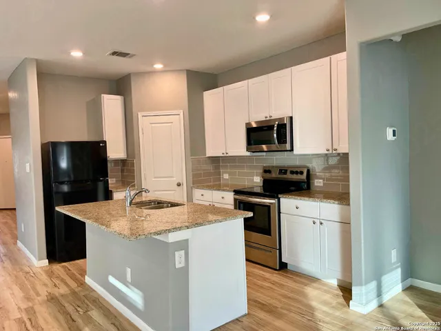 a kitchen with kitchen island granite countertop a sink stove and refrigerator