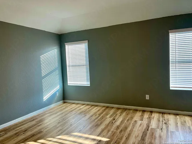a view of empty room with wooden floor and fan