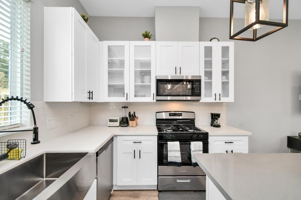 407 Stonework Oaks Lane Houston, TX 77076 - Photo 26 of 34 a kitchen with stainless steel appliances a stove a sink and white cabinets