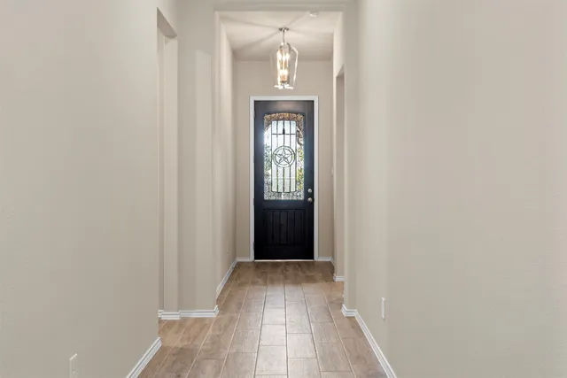 a view of a hallway with wooden floor and a mirror