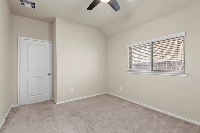 an empty room with chandelier fan and windows