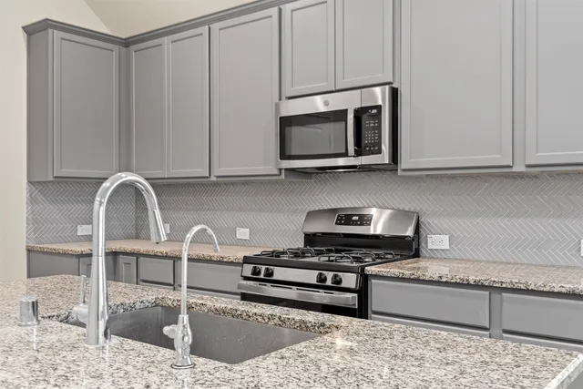 a kitchen with stainless steel appliances granite countertop a sink a stove and a microwave