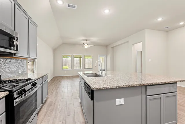 a kitchen with granite countertop a sink stove and refrigerator