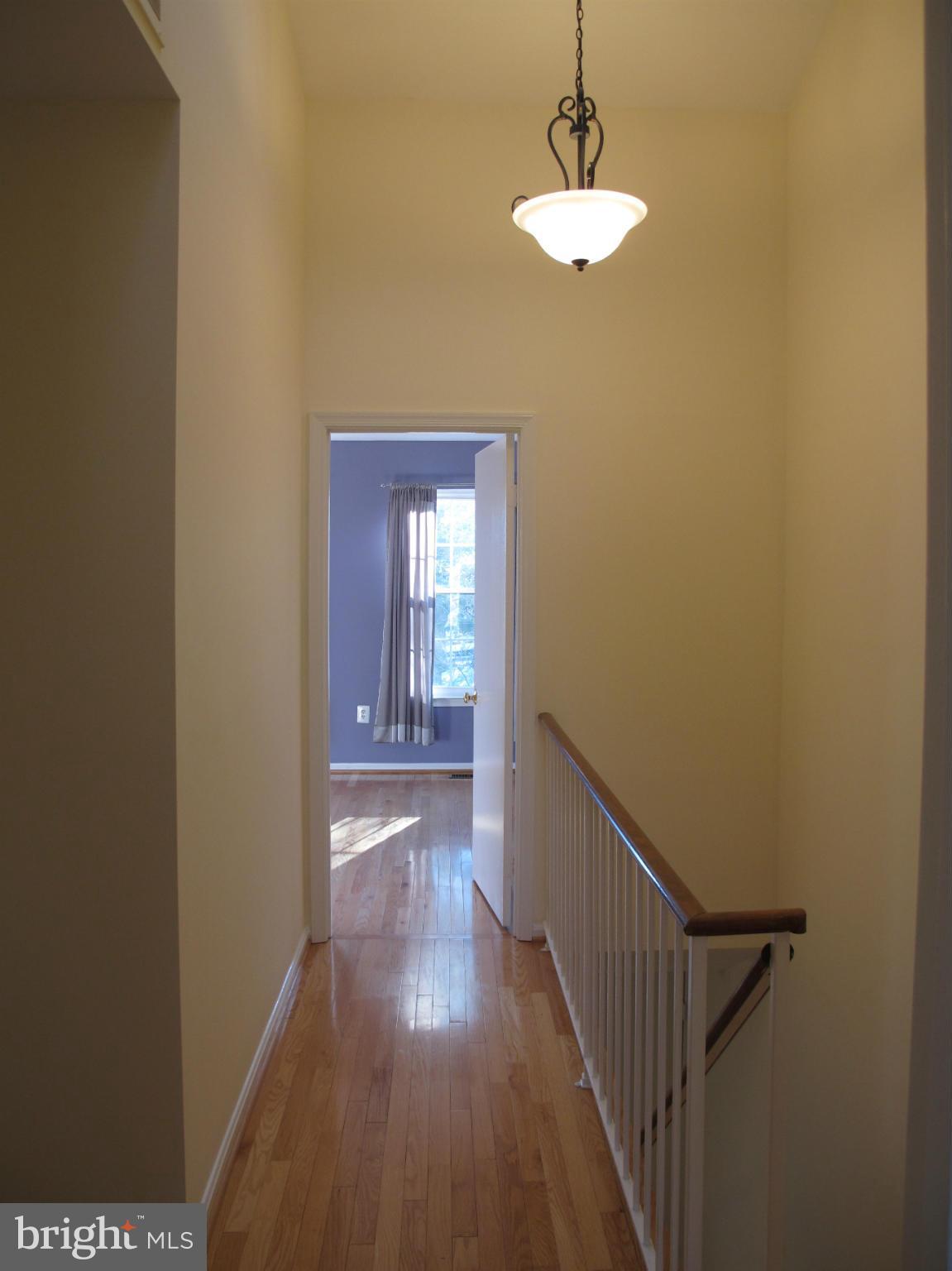 7726 Asterella Court Springfield, VA 22152 - Photo 12 of 22 a view of a hallway with wooden floor and a chandelier
