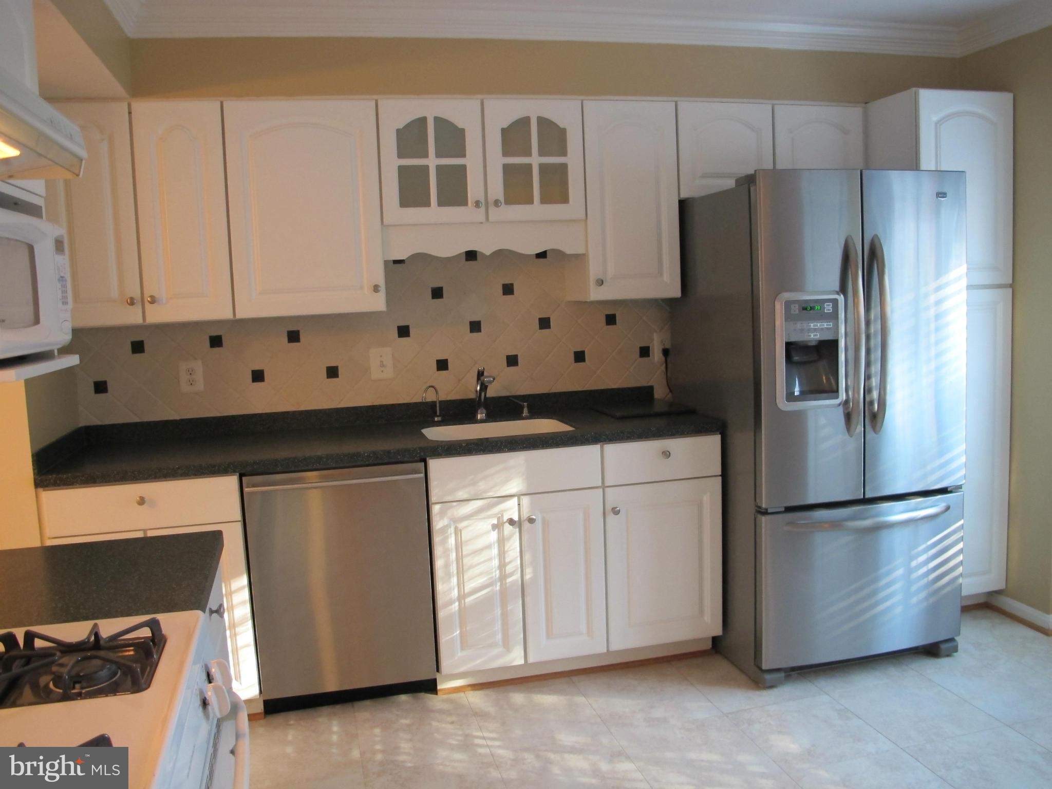 7726 Asterella Court Springfield, VA 22152 - Photo 3 of 22 a kitchen with granite countertop white cabinets and stainless steel appliances