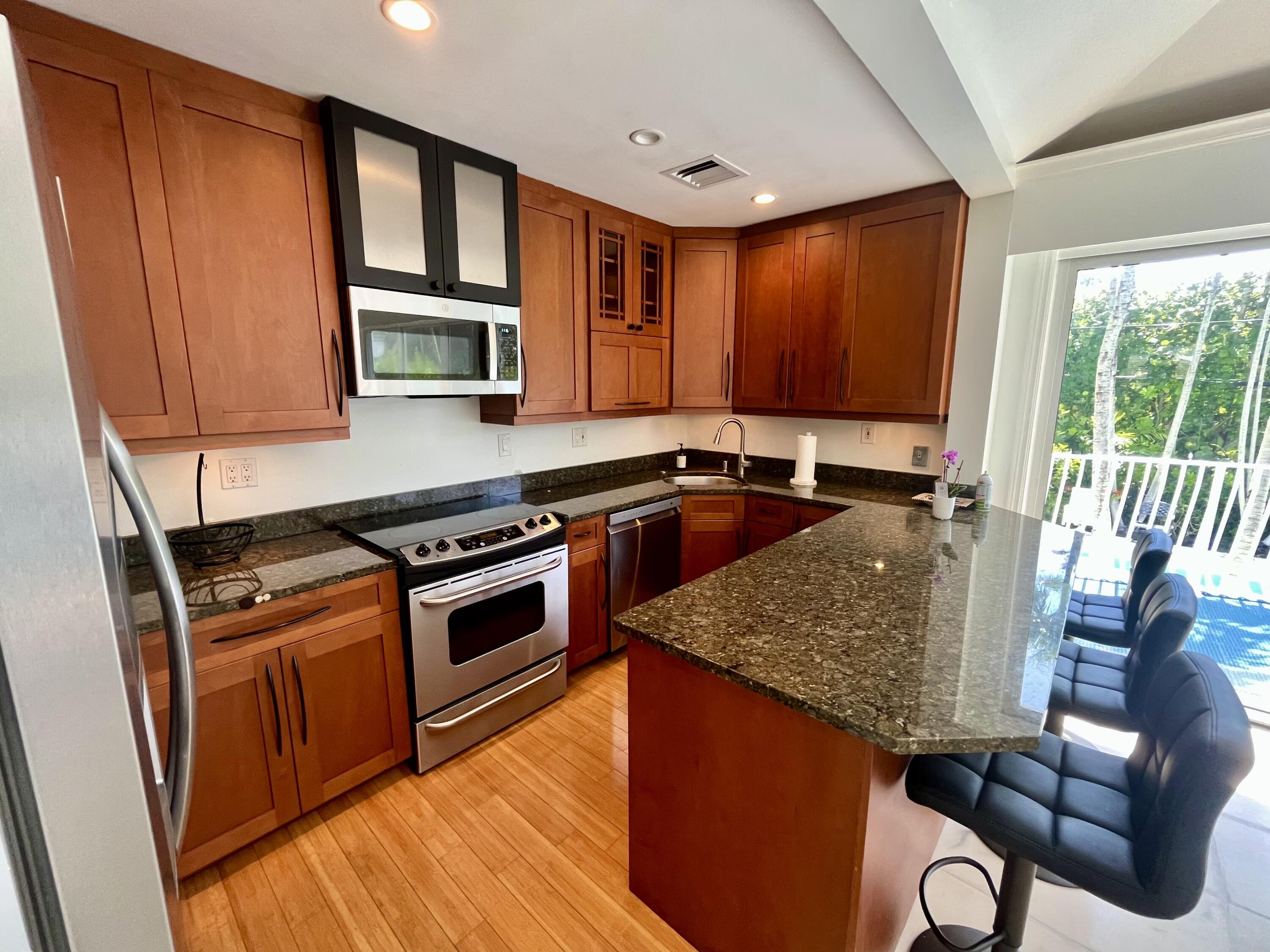 115 Dolphin Road Ocean Ridge, FL 33435 - Photo 24 of 38 a kitchen with stainless steel appliances granite countertop a stove a sink dishwasher and microwave with wooden floor