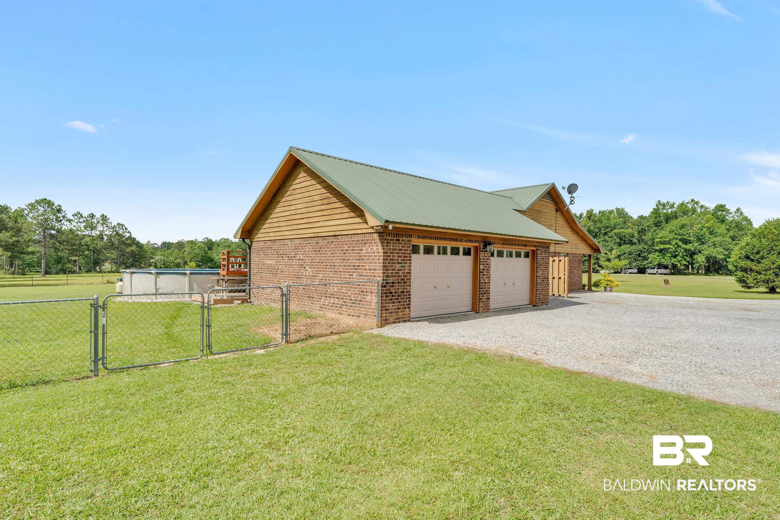 4062 River Road Theodore, AL 36582 - Photo 8 of 32 View of side of property with a gate, a garage, brick siding, and gravel driveway