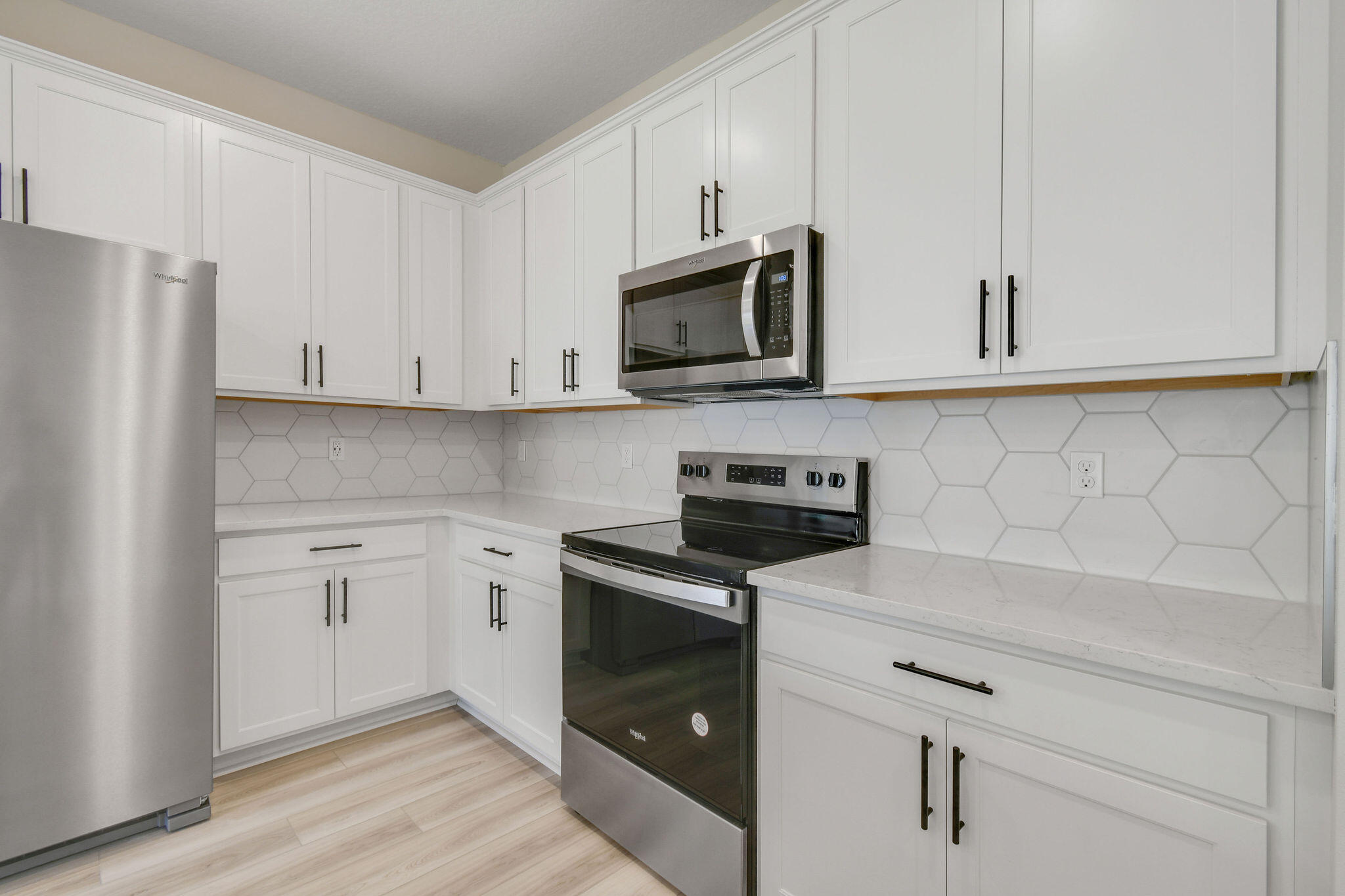 7776 Southwest Bentley Lane, Unit NAUTICAL 7414 Stuart, FL 34997 - Photo 6 of 22 a kitchen with stainless steel appliances white cabinets and a stove top oven
