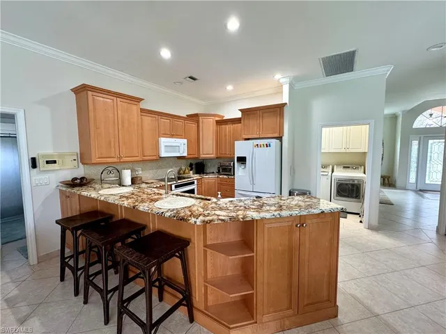 a kitchen with stainless steel appliances granite countertop wooden cabinets a dining table and chairs