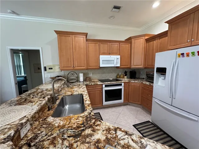 a kitchen with granite countertop a sink stainless steel appliances and cabinets
