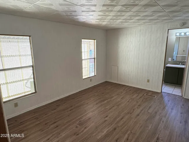 an empty room with wooden floor cabinet and windows