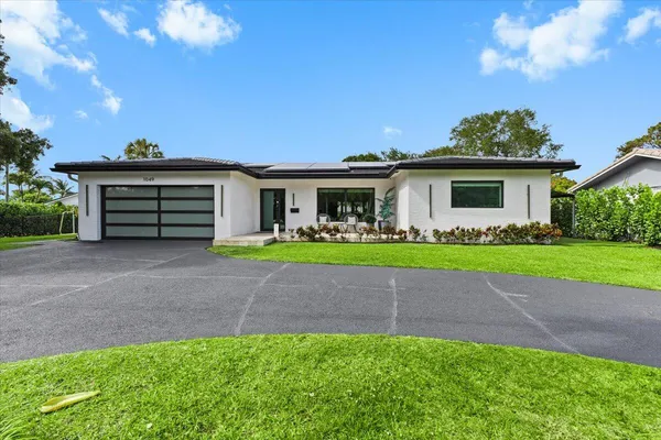 a front view of a house with a garden and trees