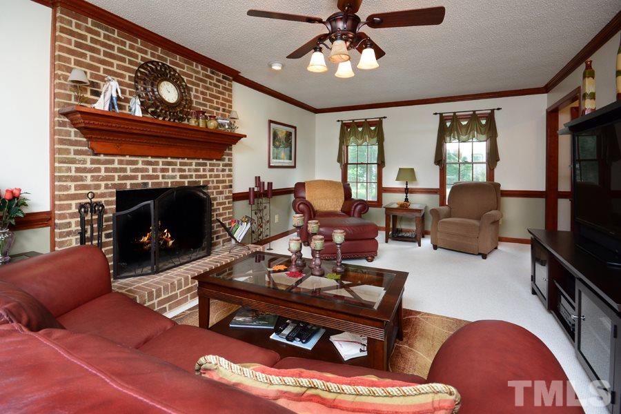 6013 Hampton Ridge Road Raleigh, NC 27603 - Photo 3 of 25 a living room with furniture a chandelier and a fireplace