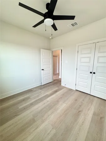 an empty room with ceiling fan and window