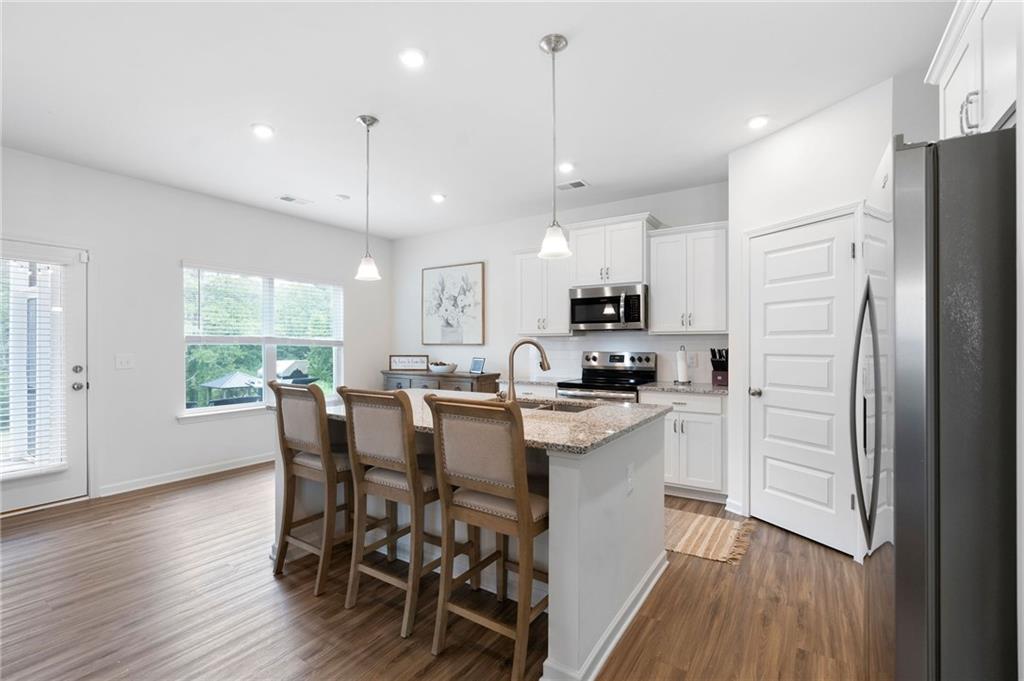 110 Waterside Ridgg Calhoun, GA 30701 - Photo 13 of 31 a kitchen with kitchen island wooden floors and white appliances