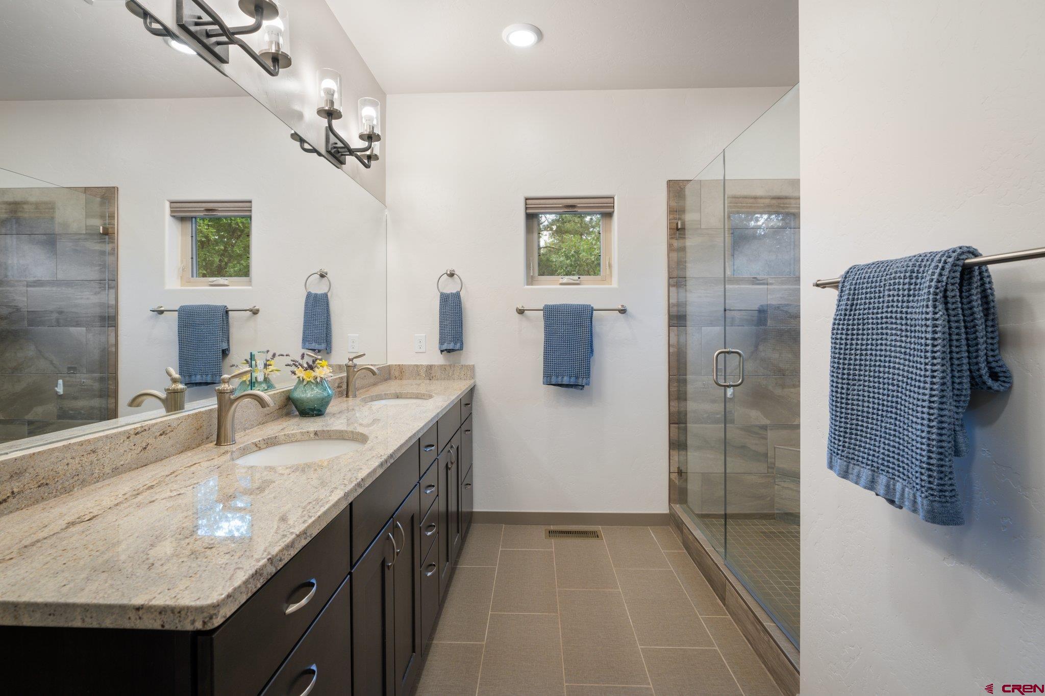 65 Needle Creek Trail Durango, CO 81301 - Photo 19 of 35 a bathroom with a granite countertop sink a shower a mirror and a bathtub