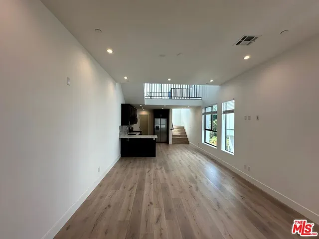 a view of a hallway with wooden floor and a kitchen