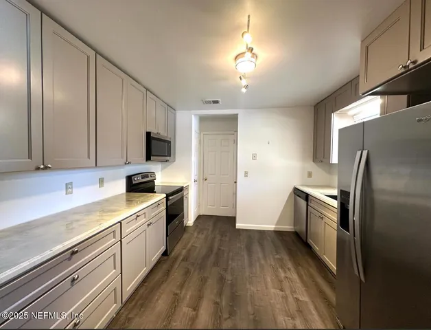 a kitchen with a sink a counter top space stainless steel appliances and cabinets