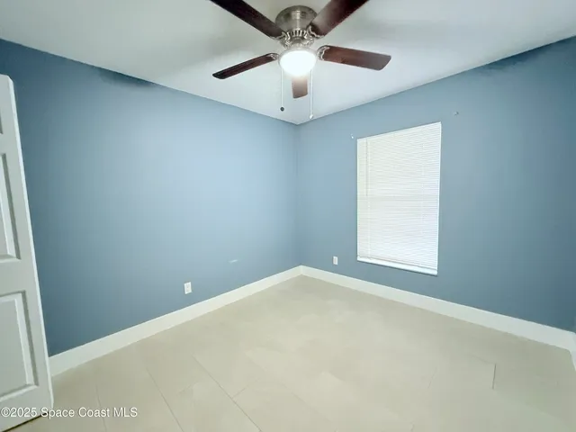 an empty room with a window and a fan