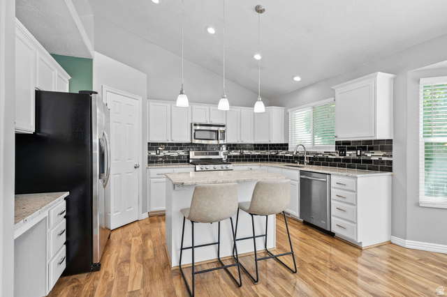 142 East 2675th Street South Clearfield, UT 84015 - Photo 8 of 49 Kitchen featuring white cabinetry, wood-finish flooring, and a stone-finish island with pendant lighting