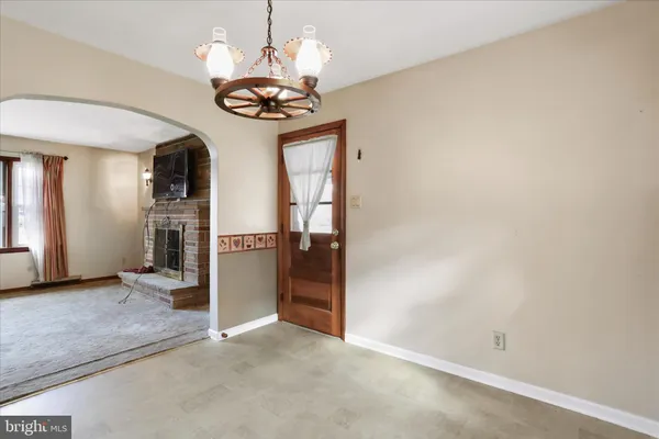 an empty room with kitchen view and a chandelier