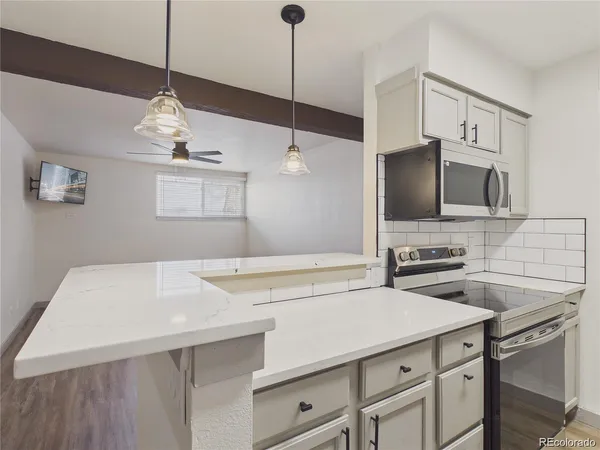a kitchen with a sink a microwave a stove and white cabinets