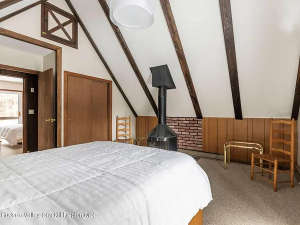 a bedroom with a bed a mirror and a flat tv screen on the dresser
