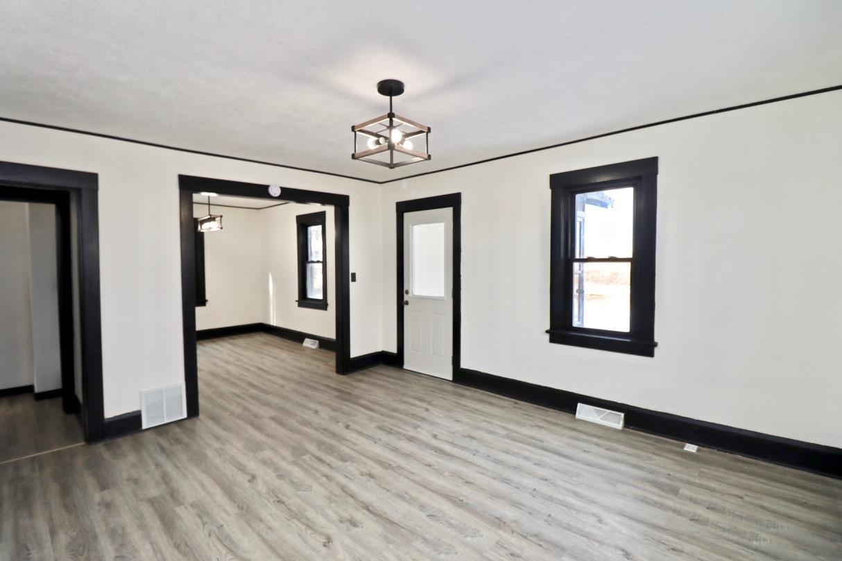 15738 Farm School Road Durand, IL 61024 - Photo 5 of 20 an empty room with wooden floor chandelier and windows