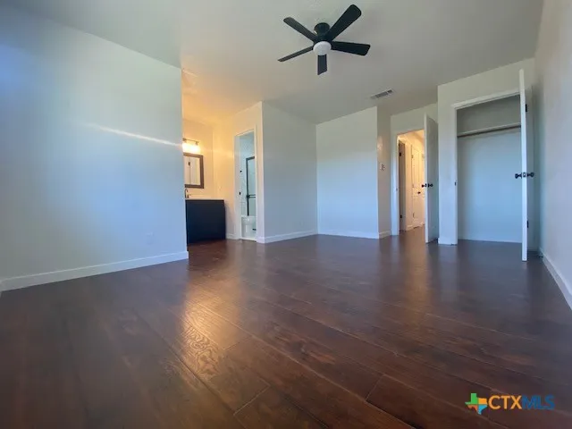 a view of an empty room with wooden floor and a mirror