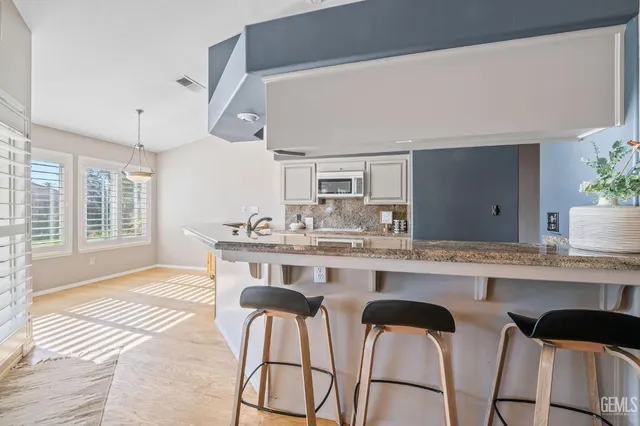 a kitchen with a dining table chairs cabinets and stainless steel appliances