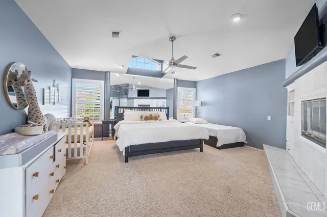 a bedroom with a bed a flat screen tv and a fireplace