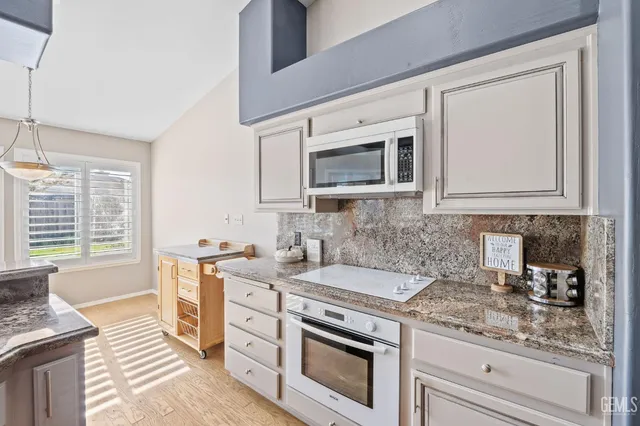 a kitchen with stainless steel appliances granite countertop a stove a sink and a microwave