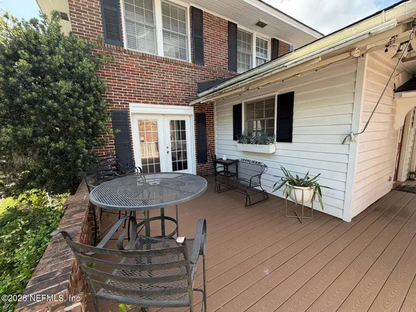 a view of a patio with table and chairs with wooden floor and fence