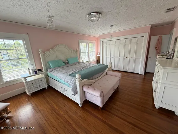 a spacious bedroom with a bed and wooden floor