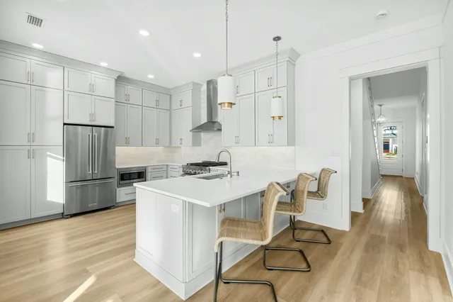 a kitchen with stainless steel appliances a refrigerator a stove a sink dishwasher and a refrigerator with wooden floor