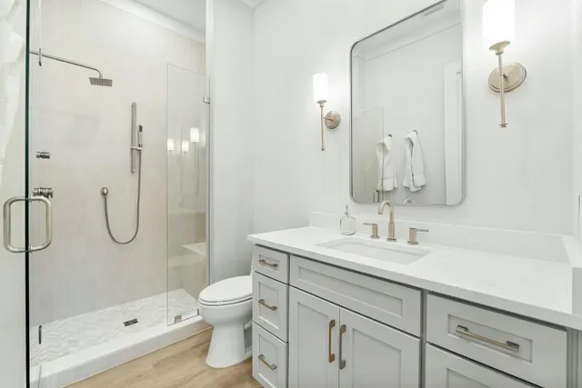 a bathroom with a shower sink vanity mirror and toilet