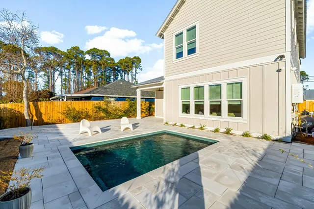 a view of a house with pool fire pit and chairs in patio
