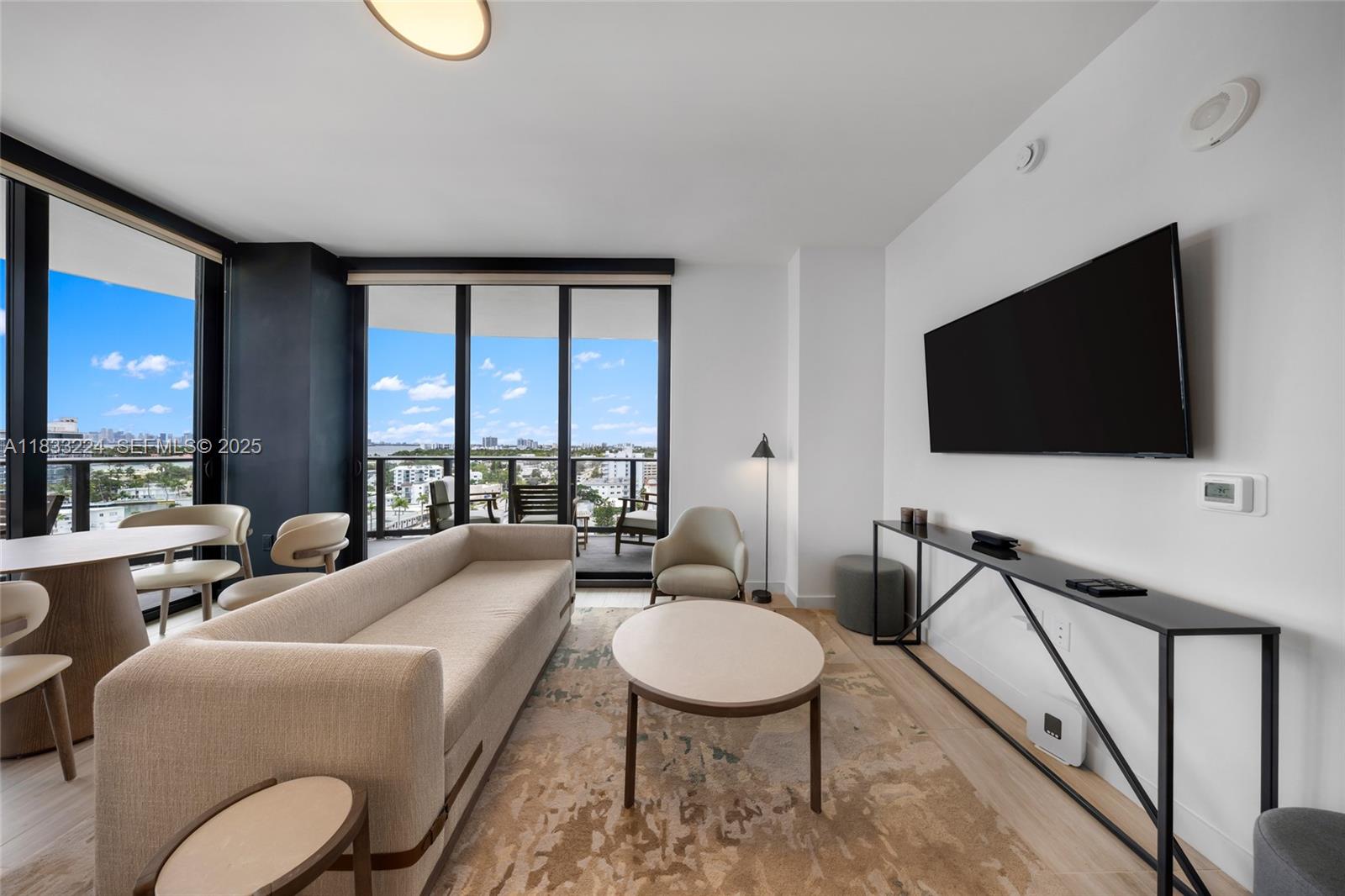 580 72nd Street, Unit 910 Miami Beach, FL 33141 - Photo 29 of 60 a living room with furniture a flat screen tv and a floor to ceiling window