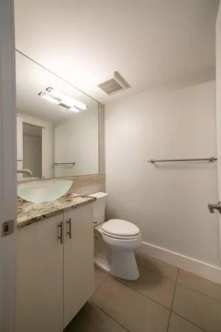 a bathroom with a granite countertop sink a toilet and a mirror