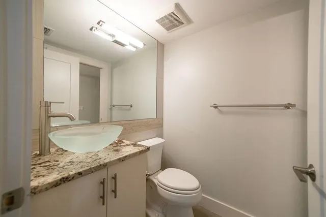 a bathroom with a granite countertop sink toilet and a mirror