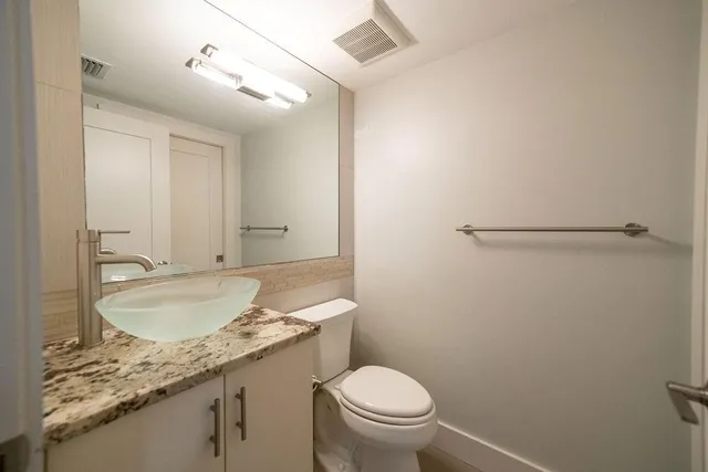 a bathroom with a granite countertop sink toilet and a mirror