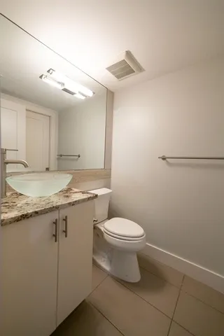 a bathroom with a granite countertop sink toilet and a mirror