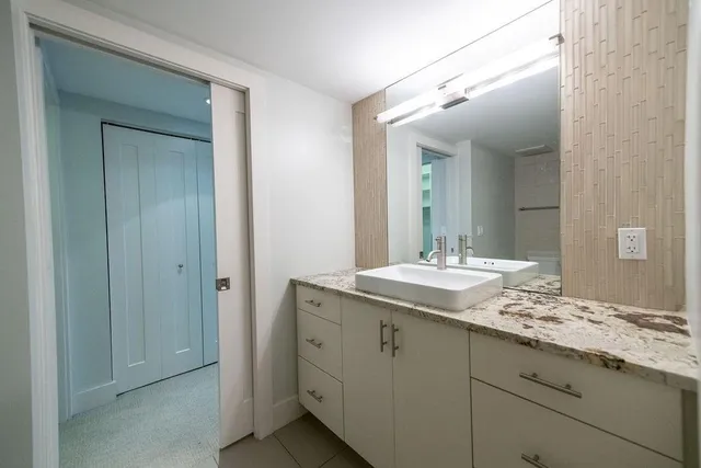 a bathroom with a granite countertop sink and a mirror
