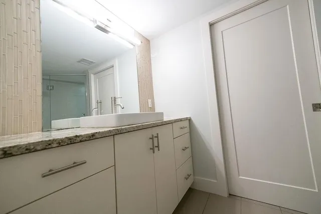 a bathroom with a granite countertop sink and a mirror