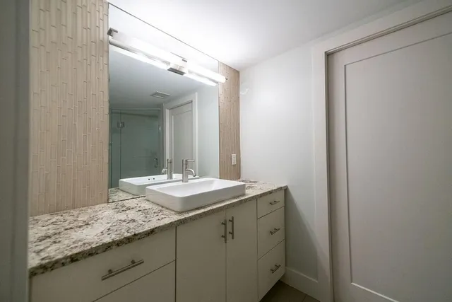 a bathroom with a granite countertop sink and a mirror